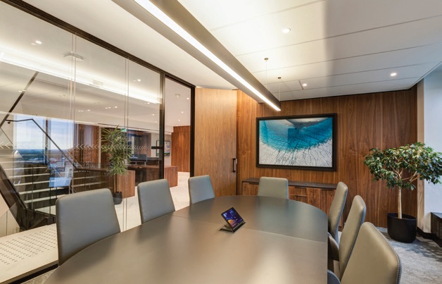 A meeting room with a long table, wood finishes and a wall-mounted display.