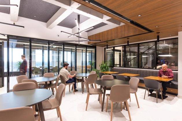 A shared office space with tables, chairs and windows overlooking downtown.